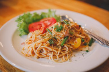 Domates soslu spagetti ve koyu ahşap bir yüzey üzerinde beyaz bir kasede fesleğen.