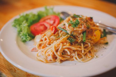 Domates soslu spagetti ve koyu ahşap bir yüzey üzerinde beyaz bir kasede fesleğen.