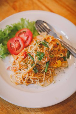 Domates soslu spagetti ve koyu ahşap bir yüzey üzerinde beyaz bir kasede fesleğen.