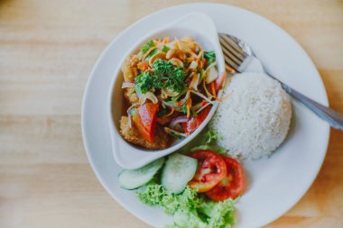 Masaya konmuş baharatlı yağda kızartılmış yayın balığı salatası.