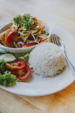 Masaya konmuş baharatlı yağda kızartılmış yayın balığı salatası.