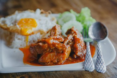 Buharda pişmiş domuz ve pilav ve ahşap masada kızarmış yumurta.