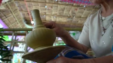 Kadın elleri çömlek çarkında çalışıyor ve tencere yapıyor.