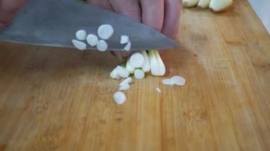 Tahta kesme tahtasının üzerinde dilimlenmiş taze yeşil soğanlar.