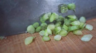 Tahta kesme tahtasının üzerinde dilimlenmiş taze yeşil soğanlar.