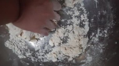 Hamur yoğuran elleri pişir, beyaz buğday unu serpiştir.
