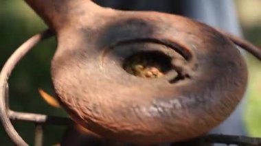 Kahve çekirdekleri, bir eski El değirmeni kavurma için aygıt. Dumanlı kızartma kahve bir ahşap stand. Stüdyo aydınlatma.