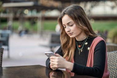 Kafede akıllı telefonu olan genç bir kadın.