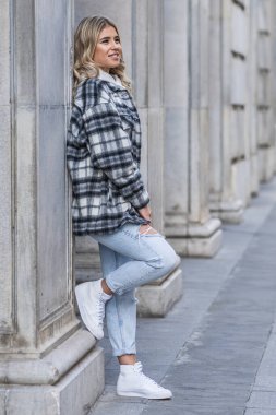 Sarı halkalı genç bir kadın ayakta duran sütunlara yaslanıyor.