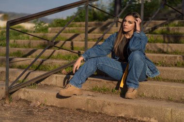 Gündelik giysiler içinde merdivenlerde oturan güzel genç bir kadın.