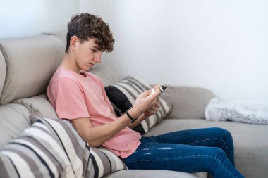 Genç bir çocuk oturma odasında kitap okuyor. Eğitim kavramı