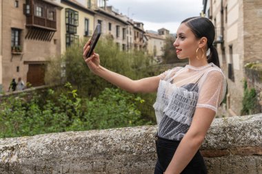 Beyaz bir kadın akıllı telefonuyla selfie çekiyor.