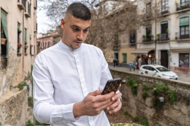 Kafkasyalı genç esmer adam akıllı telefona bakıyor.