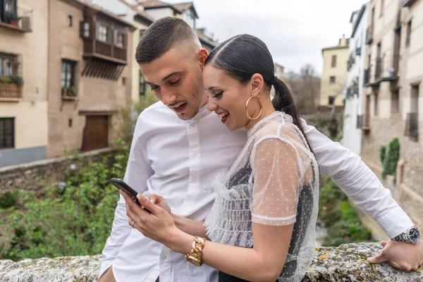 Casal apaixonado sorrindo ao ver algo no smartphone — Fotografia de Stock
