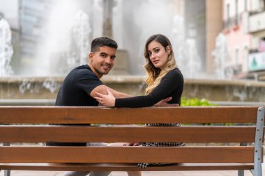 Şehirde bir bankta oturan aşık genç İspanyol çift.