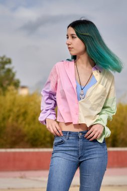 Turkuaz saçlı genç kız dik dik dik bakıyor.