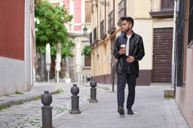 Sakallı beyaz bir adam, şehirde kahve içiyor.