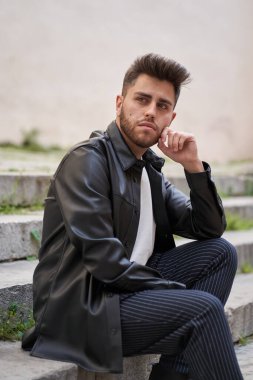 Siyah deri ceket giymiş, sakallı, beyaz bir adam.