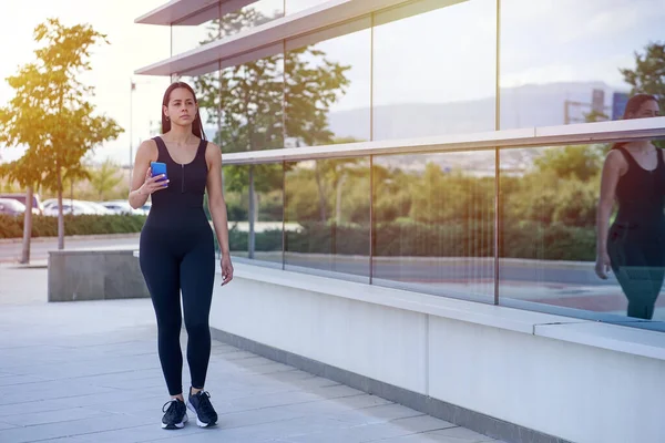 Žena modelka se sportovním oblečením a fit tělo chůze s smartphonem — Stock fotografie