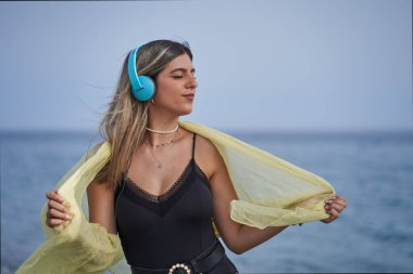 young woman enjoying music with her headphones on the beach