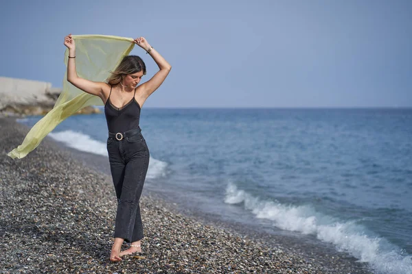 Jeune femme dansant sur la plage avec une écharpe jaune — Photo