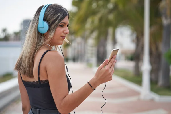 Jeune femme écoute de la musique avec téléphone intelligent sur la promenade — Photo