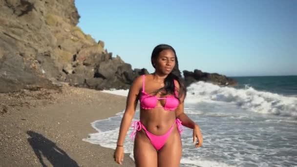 African american woman walking along the shore of the beach in a bikini — Vídeo de Stock