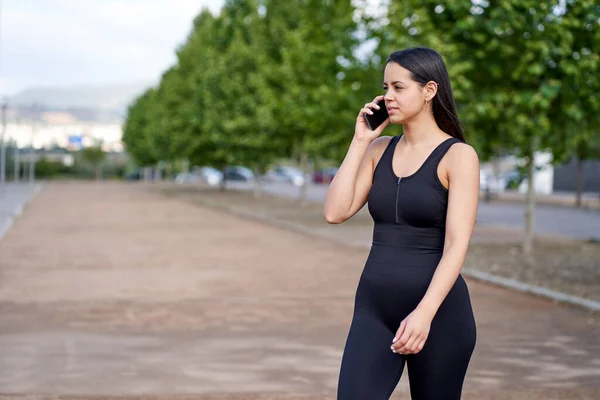 Młoda kobieta z dopasowanym ciałem rozmawia z telefonem komórkowym — Zdjęcie stockowe