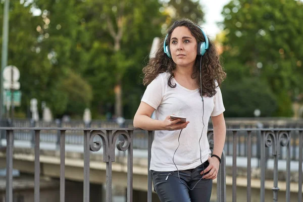 Femme écoute de la musique avec son casque connecté à son smartphone — Photo