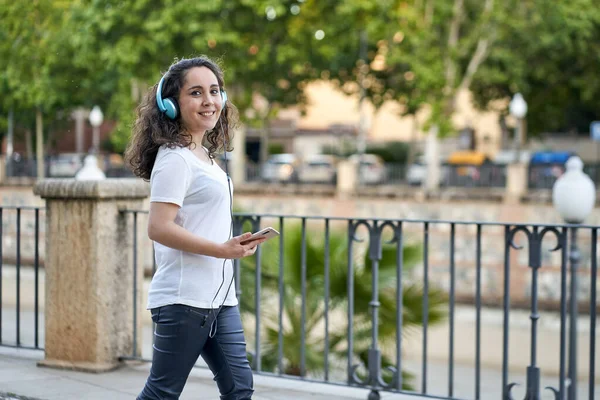 Femme écoute de la musique avec son casque connecté à son smartphone — Photo