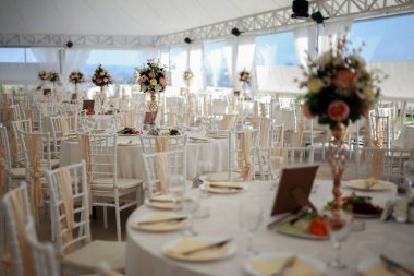 Sandalyeler ve masa çiçeklerle süslenmiş çatal bıçaklar ve çanak çömlekle servis edilmiş ve masa örtüsüyle örtülmüş. Özel düğün konsepti