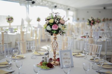 Sandalyeler ve masa çiçeklerle süslenmiş çatal bıçaklar ve çanak çömlekle servis edilmiş ve masa örtüsüyle örtülmüş. Özel düğün konsepti