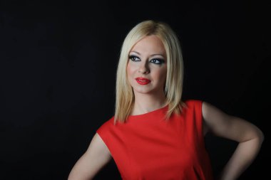 ? Stüdyoda siyah arka planda kırmızı elbiseli çok güzel ve çekici bir kızın fotoğraf çekimi.