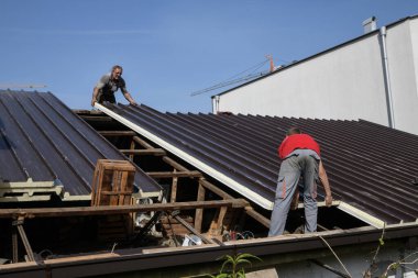 İnşaat alanındaki çatı inşaatında çalışan iki işçi.