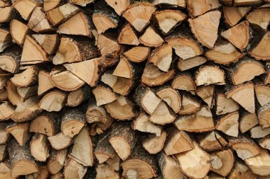 Yakacak odun dokusu, kırsal kesimin kahverengi arka planını gösteriyor. Kışa hazır odun yığını. Doğranmış odun yığını istiflemeye hazır.