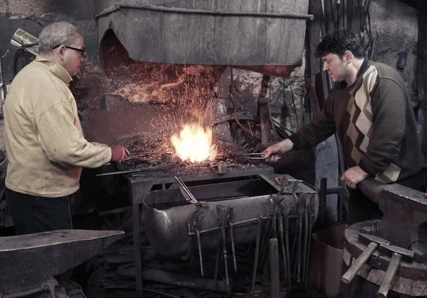 Blacksmith heats iron in the fire on workshop