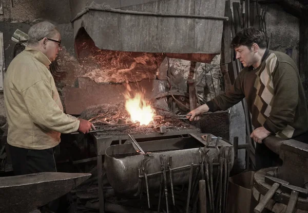 Blacksmith heats iron in the fire on workshop