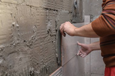 Duvara fayanslar yapıştırıyorum. Duvara fayanslar seriyorum. İşçi duvarlara büyük seramik fayanslar yerleştiriyor