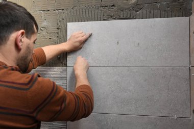 Duvara fayanslar yapıştırıyorum. Duvara fayanslar seriyorum. İşçi duvarlara büyük seramik fayanslar yerleştiriyor