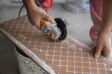 Seramik fayanslar kesiliyor. Bir işçi kesme makinesine büyük bir seramik döşeme koyar. Fayanslarda bir delik açmak.