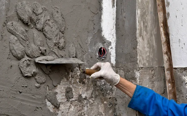 Ev inşaatının duvarına beton yapıştıran kadın işçi.