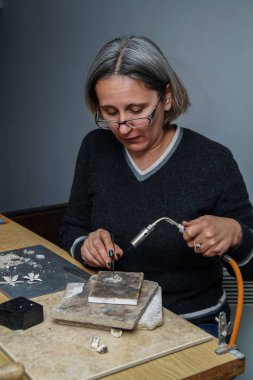 Gümüş mücevherlerin imalatı ve onarımı için yakıcı ısıtma. Isıtma feneri. Bir kadın sanatçı el yapımı gümüş mücevherler yapar.
