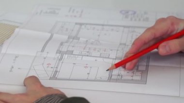 İnşaat planında gündelik giysi notları olan genç bir mimarı yakından takip edin.