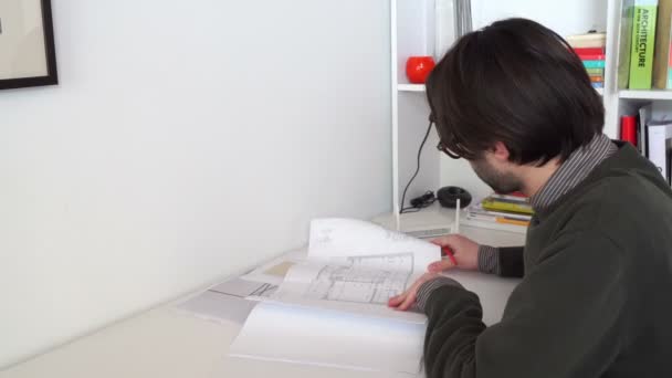 Młody Architekt Inżynier Sprawdza Rysunki Budowlane Swoim Biurze — Wideo stockowe