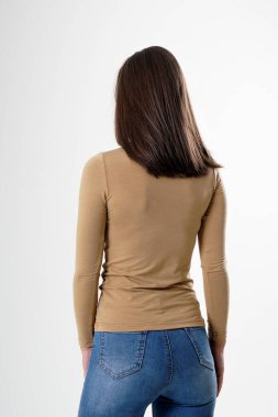 Sırtı dönük, açık kahverengi bluz ve mavi kot pantolon giyen beyaz arka planda izole bir kadın portresi. Sıra dışı ve uzun saçlı çok çekici bir kadın. Güzel saçlı bir kız, beyaz bir sirk grubunda seyirciye sırtını döndü.