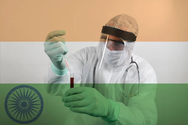 Doctor wearing respiratory mask and holding the Coronavirus Covid-19 blood sample. Scientists test for Covid-19 or Corona virus By using science tubes to research and treat illness in a lab or hospital. Transparent flag of India over the photo