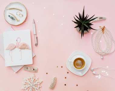 Not defteri, kahve fincanı, aksesuarlar ve blog konseptiyle pembe kadınsı çalışma alanı. Düz yatış, üst görünüm