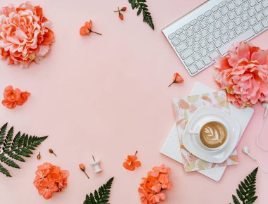 Üst Manzara Freelancer ofis masası. Pembe arka planda kahve, klavye, çiçekler ve kırtasiye ile blogger çalışma alanı 