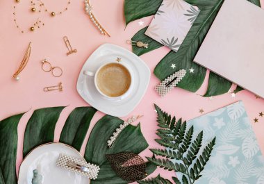 Ofis masası. Tropik düzlük. Merkez ofis çalışma alanı. Kahve fincanı ve pembe arka planda canavar yaprağı..