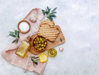 Akdeniz zeytinleri, otlar ve ekmek dilimleri sade masa, üst manzara.